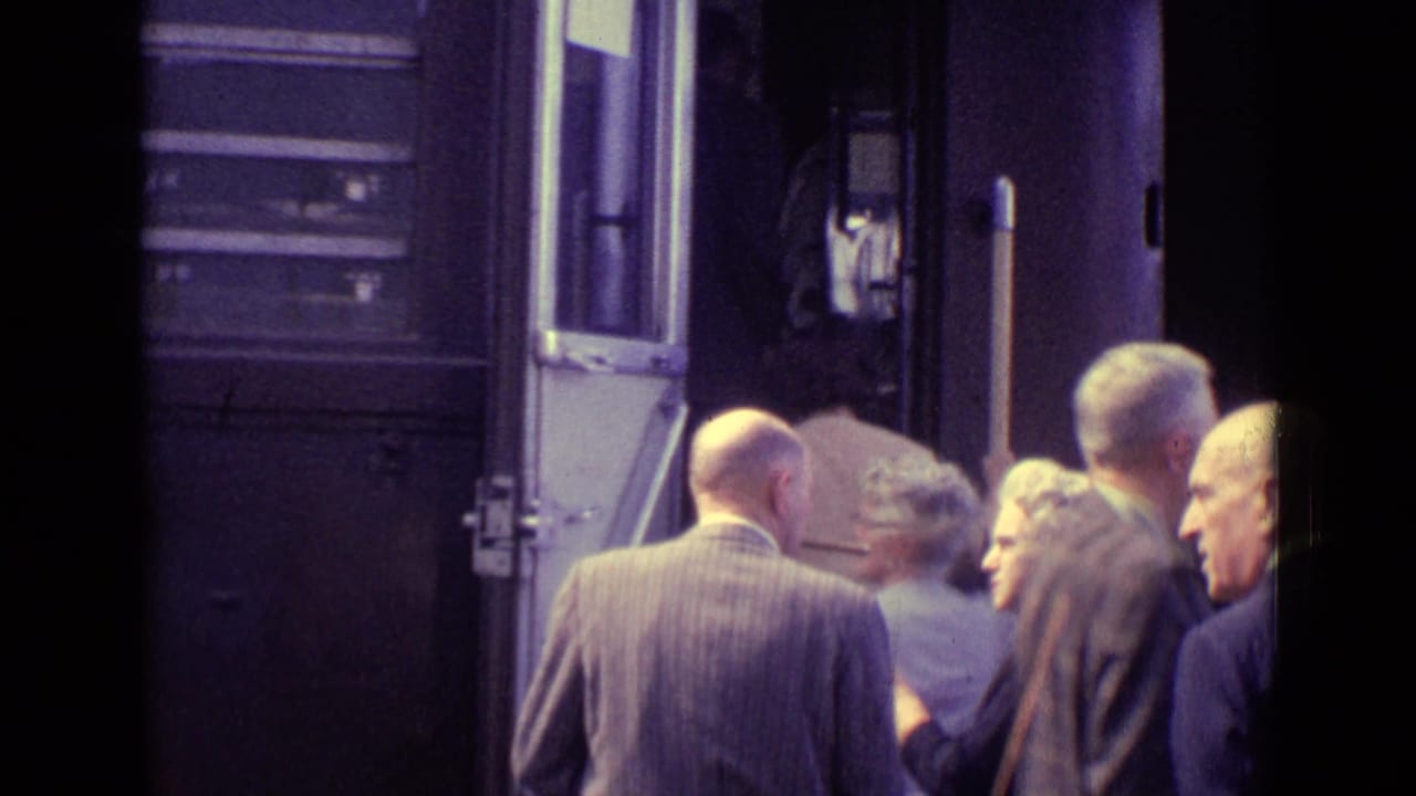 Passengers wait beside an open train door as others board.