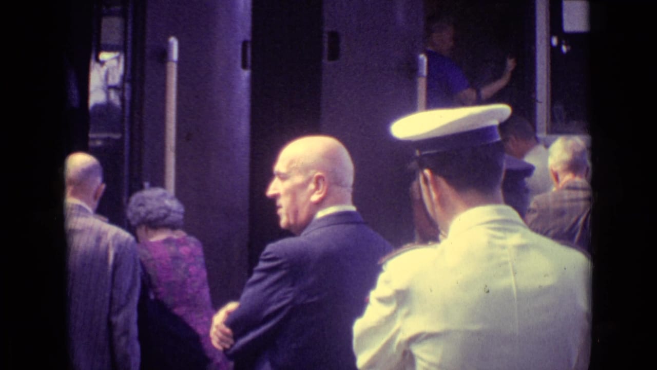 Passengers board a train while a uniformed staff member stands nearby.