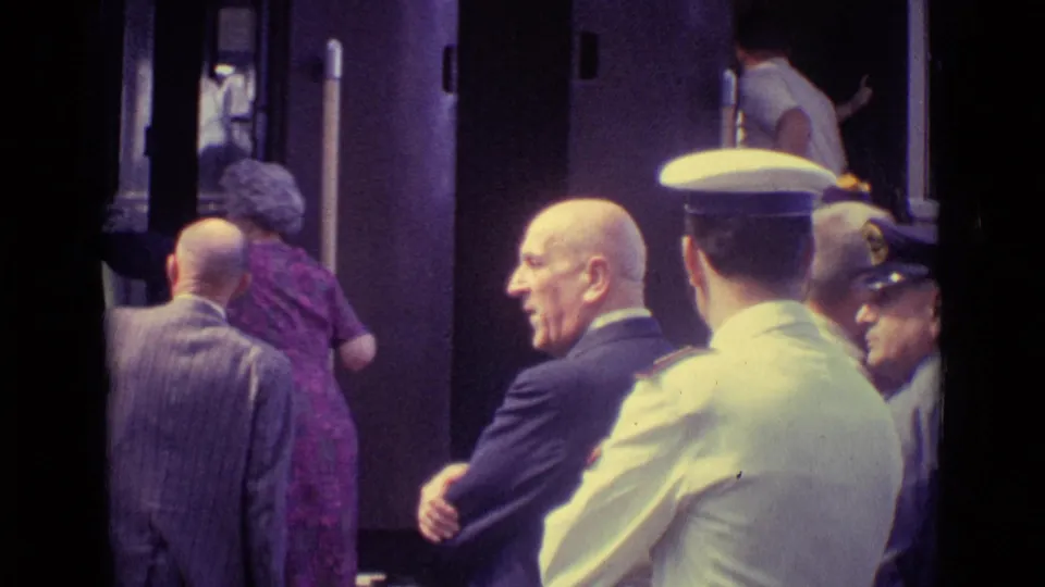 A Venice rail platform scene from 1962 with adults near an open train door and uniformed staff watching boarding.