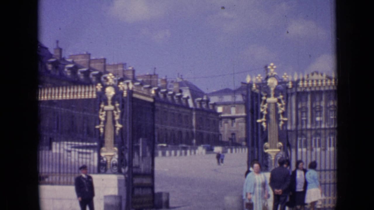 Gilded palace gate with visitors and a uniformed guard near the entrance.