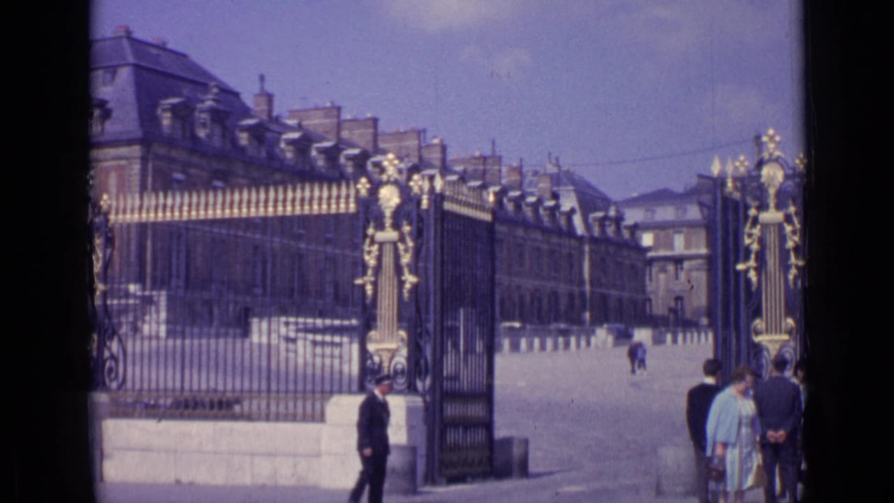 Palace gate and forecourt with visitors standing near the right edge.