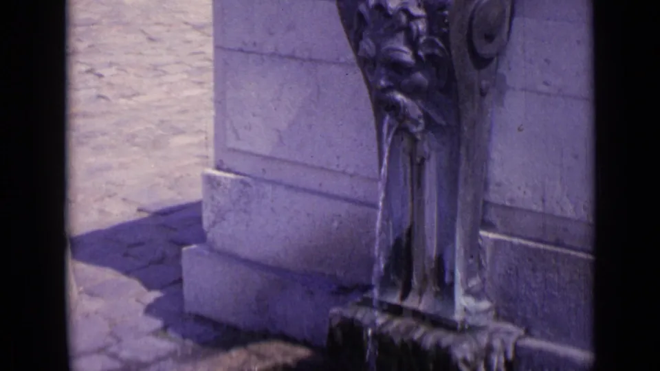 The final frame holds on the stone fountain detail, showing flowing water, carved ornament, and the surrounding masonry in daylight.