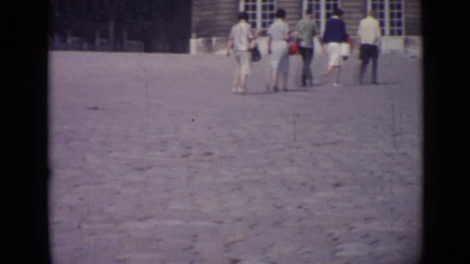 A 1962 Versailles courtyard view shows adult visitors in mid-century clothing walking toward a building with tall windows.