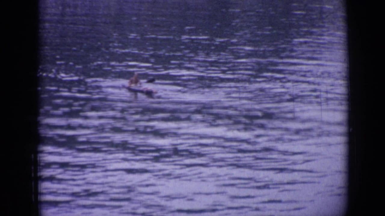 A small canoe with one paddler moves across the lake in Versailles, France, seen in a wide 8mm frame.