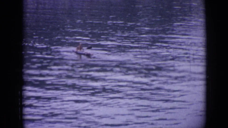 A small canoe with one paddler moves across the lake in Versailles, France, seen in a wide 8mm frame.