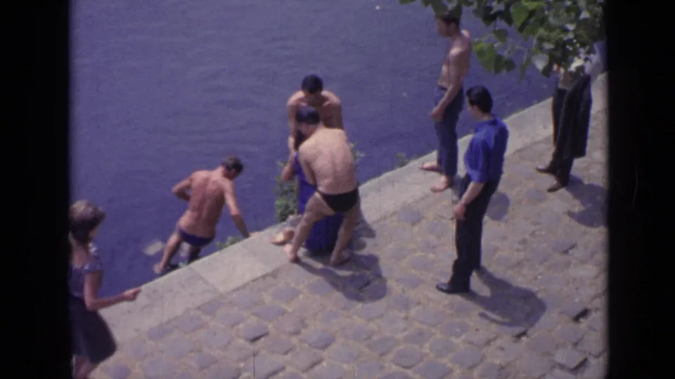 A 1962 Versailles waterside scene shows shirtless men and a woman nearby as a swimmer climbs or lowers himself from the stone edge.