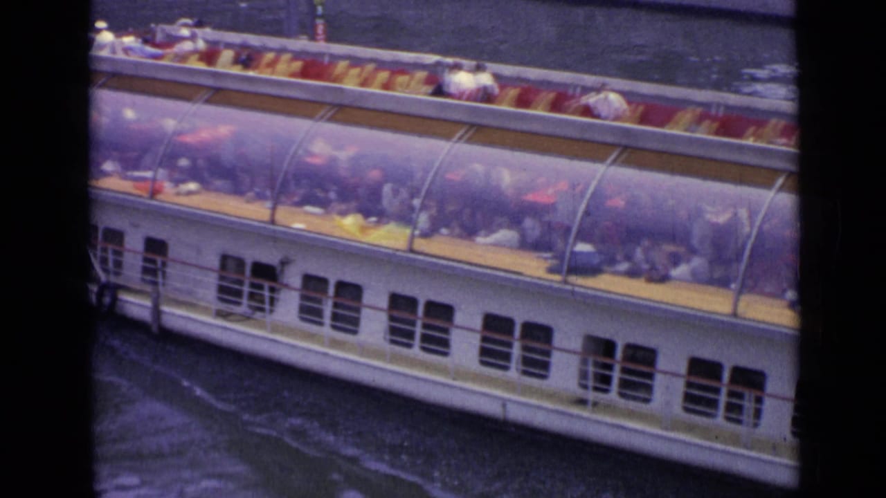 White tourist boat with covered passenger deck moving through dark river water.