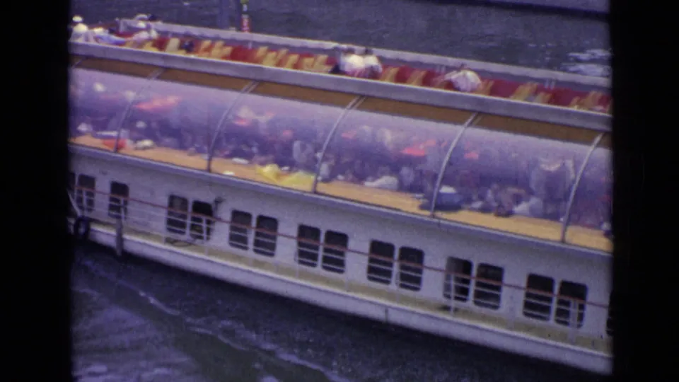 1962 Versailles footage shows a white tourist boat with a transparent canopy and seated passengers on a river.