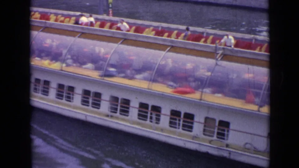 High-angle 1962 Versailles view of a river tourist boat carrying passengers beneath a curved canopy.