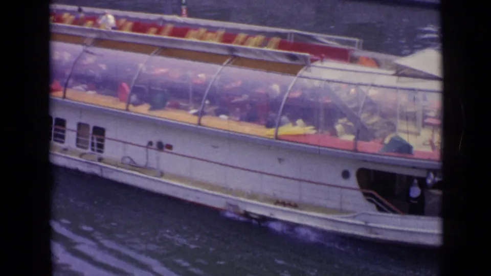 Late frame of the 1962 Versailles riverboat shot shows the bow area, canopy, seats, passengers, and water wake.