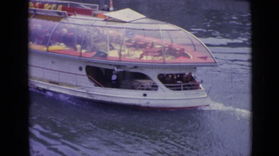 The white tour boat with a rounded glass canopy moves through the water in the 1962 Versailles home-movie footage.