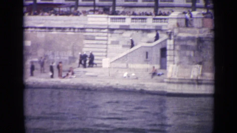 The final frame shifts to a stone waterfront in Versailles, where people gather near steps above the water.