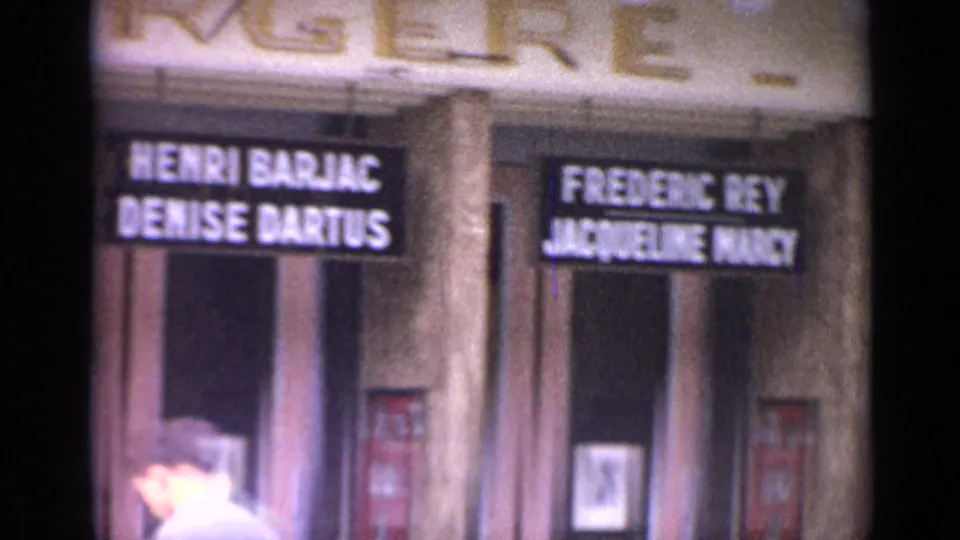 Versailles theater entrance with multiple illuminated performer-name signs and a pedestrian partly visible near the doors.
