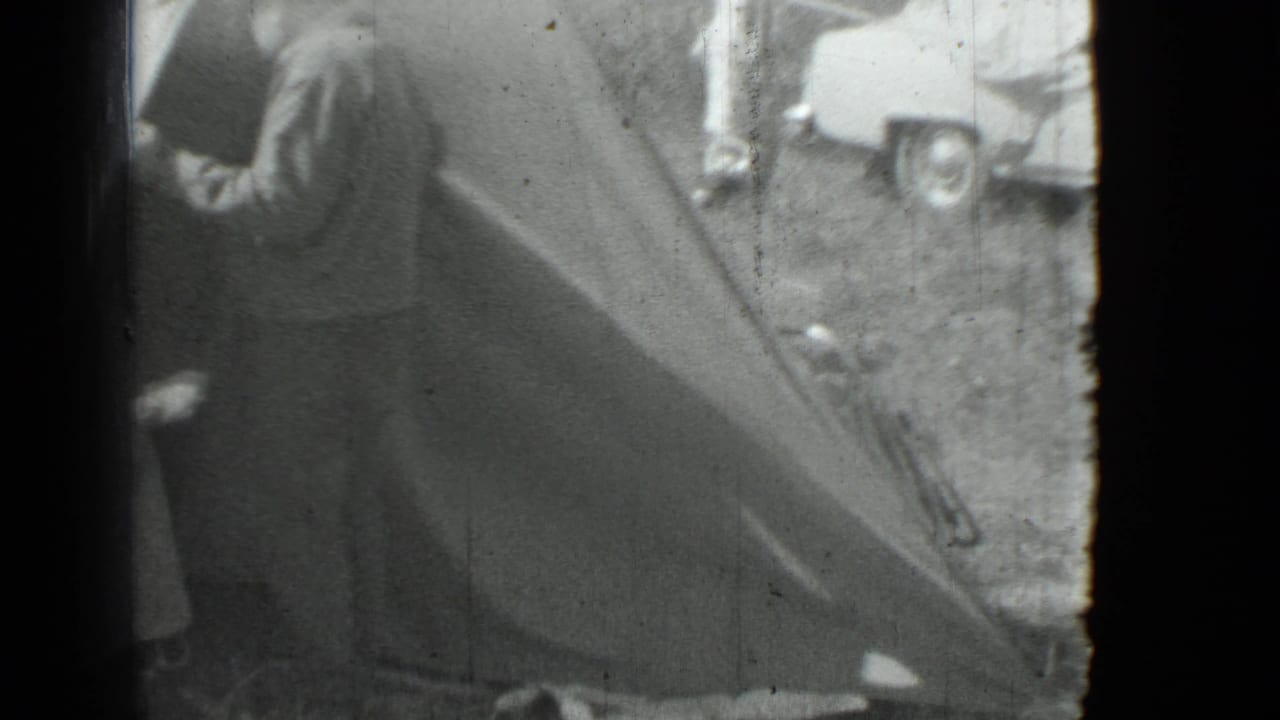 Man beside a large tent with a parked car partly visible in the background.