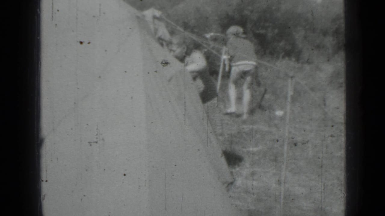 Two women stand near tent lines beside a large canvas tent.