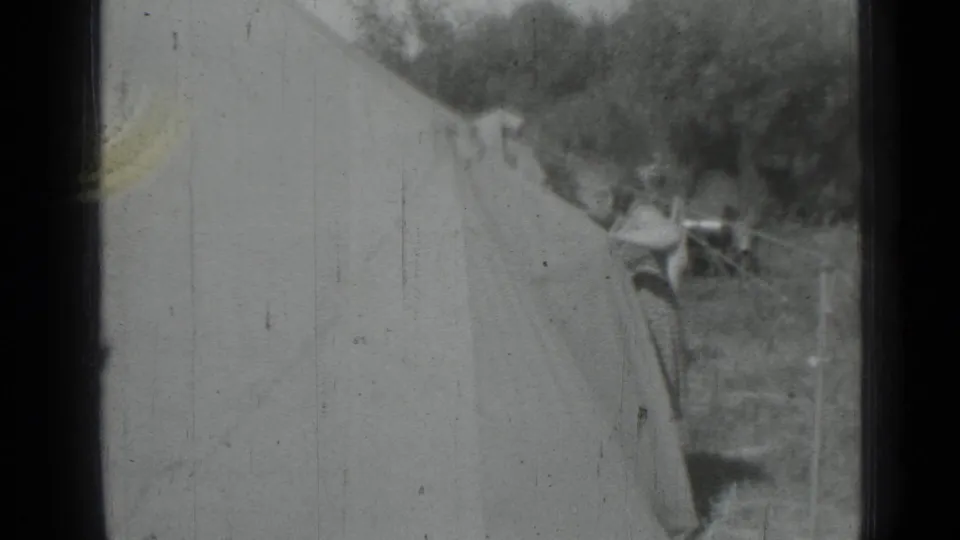 One woman crouches or bends at the tent edge while another person is partially visible near the top of the frame.