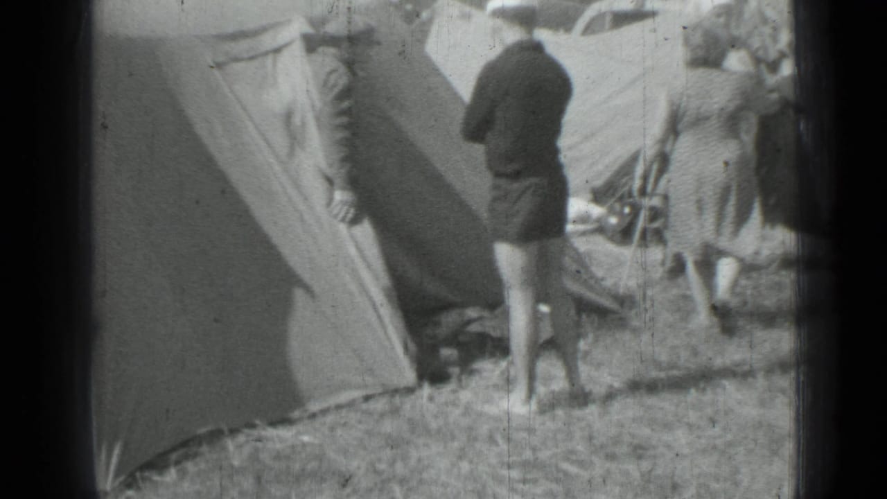 Adults gather near a canvas tent in a 1967 Saint Petersburg campsite scene, with camp gear and partial cars behind them.