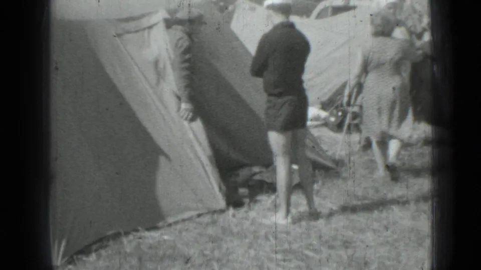 Adults gather near a canvas tent in a 1967 Saint Petersburg campsite scene, with camp gear and partial cars behind them.