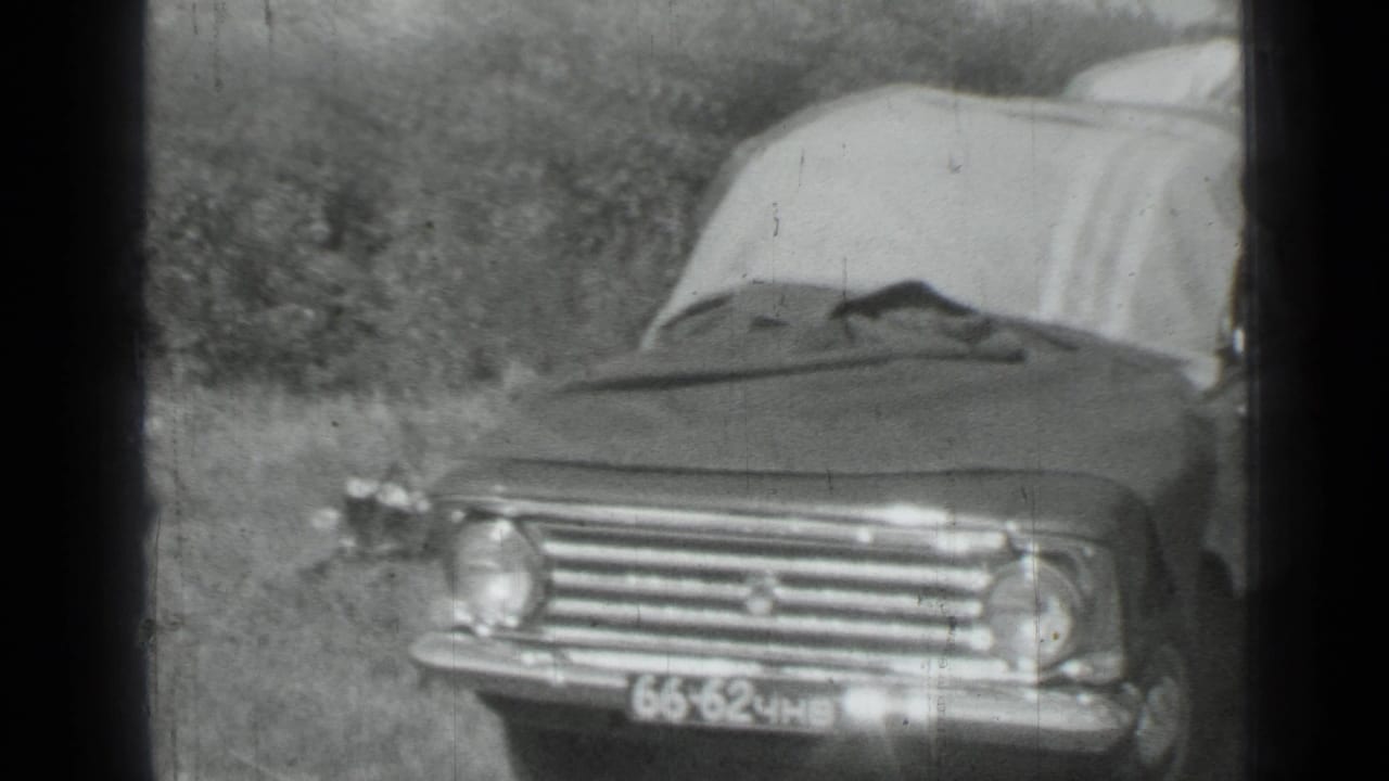 Front view of a parked sedan with blankets behind or over it, filmed in monochrome 8mm during the metadata-supported 1967 Russia trip.