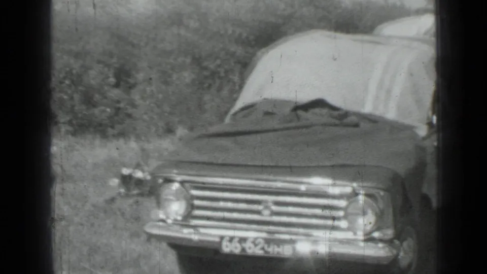 Front view of a parked sedan with blankets behind or over it, filmed in monochrome 8mm during the metadata-supported 1967 Russia trip.