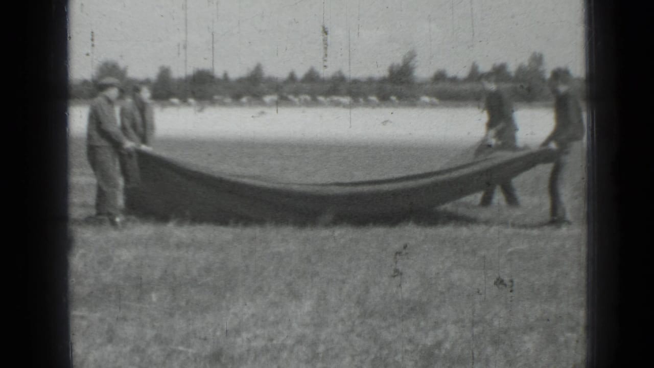 Several men stand with a sagging blanket or tarp outdoors.