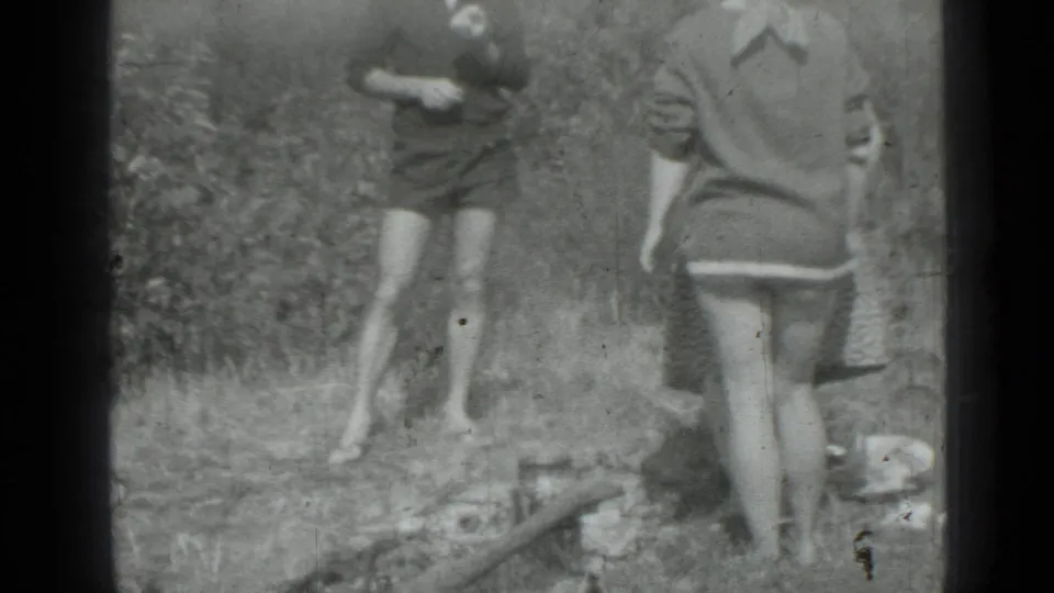 1967 8mm home-movie frame from Saint Petersburg showing two women outdoors, one near a small pan on grass.