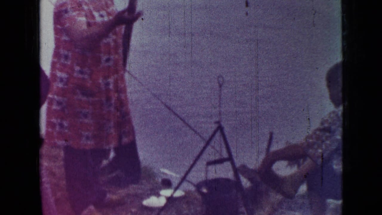 1967 Saint Petersburg 8mm frame showing a person in patterned clothing near a tripod cooking pot outdoors.