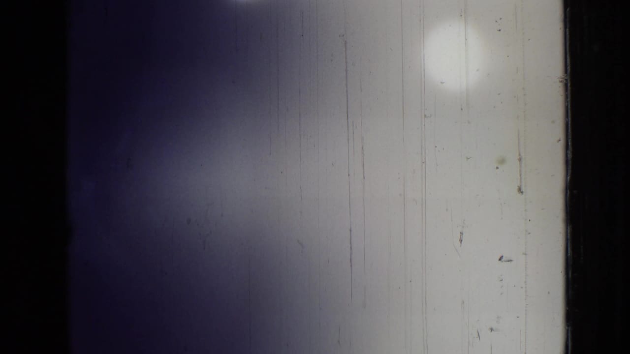 Mostly obscured film frame with pale tent-like fabric and dark borders.