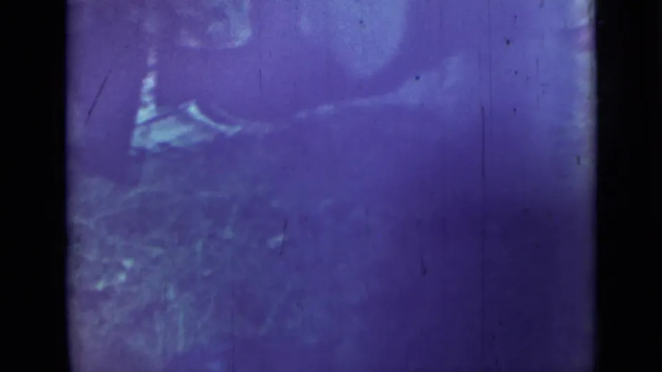 A faded 1967 Saint Petersburg home-movie frame appears to show a person bending near the fire area outdoors.