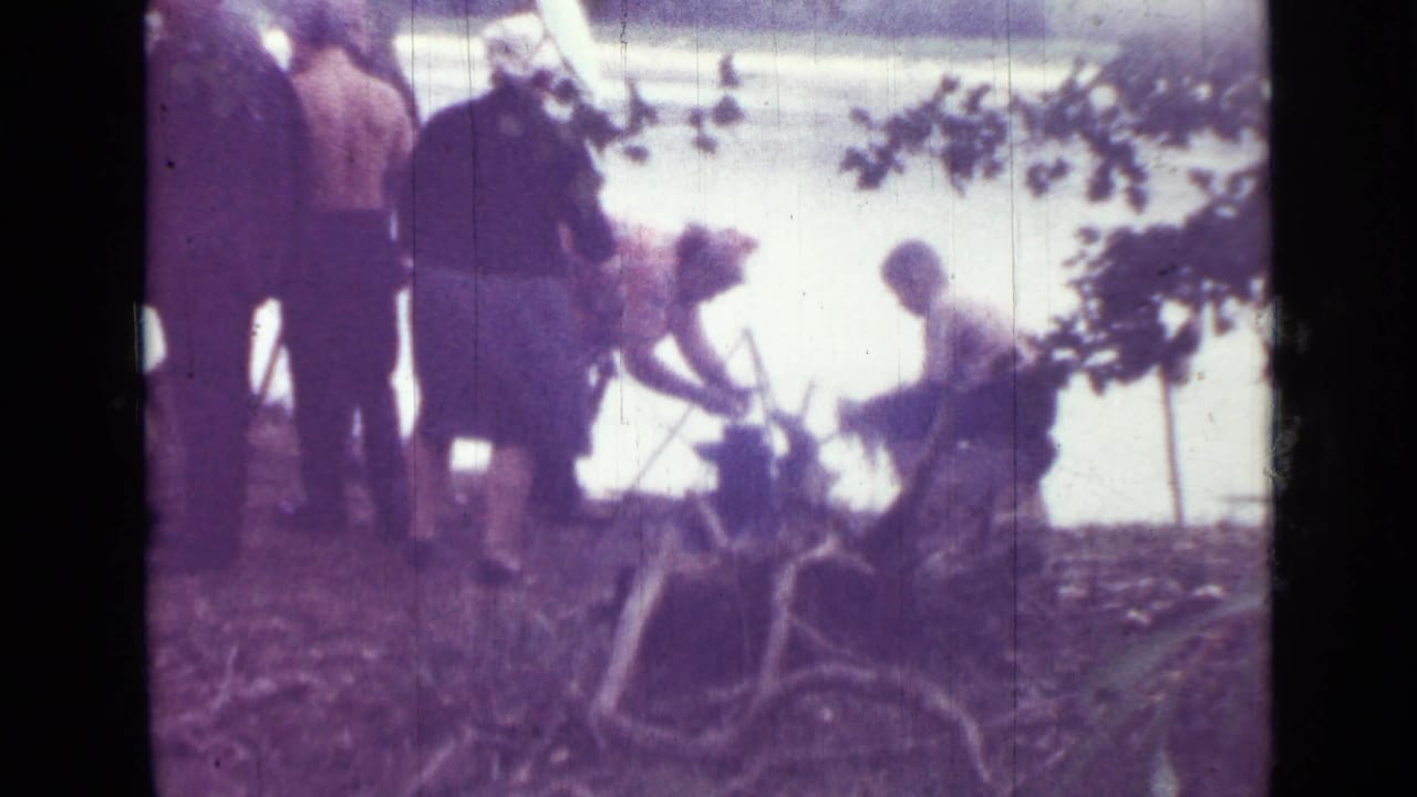 A 1967 Saint Petersburg riverbank scene shows a small group near trees while one person bends over a fire or cooking setup.
