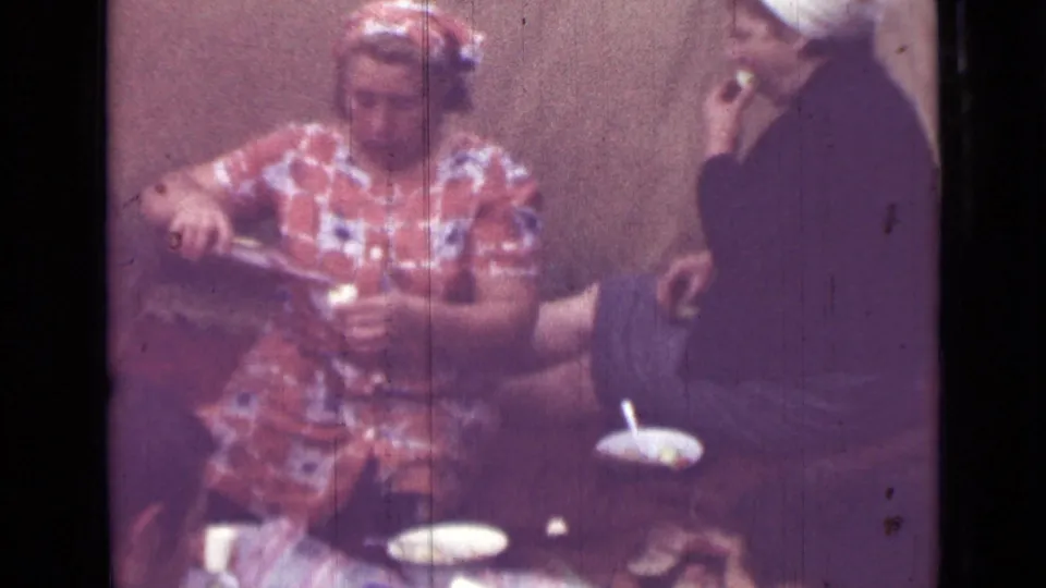 1967 Saint Petersburg home-movie still showing a woman serving at a small table as another person holds up a cup nearby.
