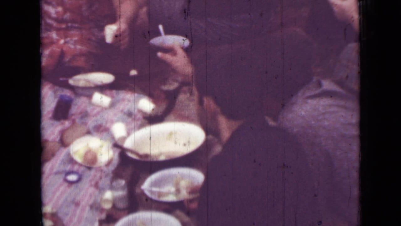 1967 Saint Petersburg 8mm still with people gathered beside a picnic spread of plates, cups, and food on a patterned blanket.