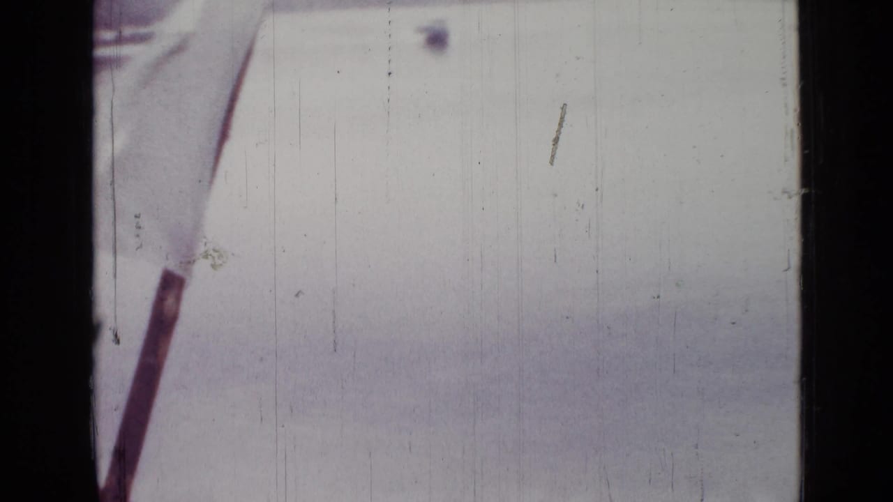 Pale lake surface with part of a pole or boat edge at the left side of the frame.