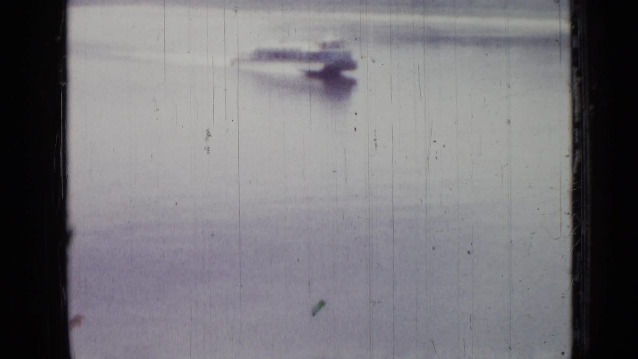 Distant motorboat continues across a hazy water surface.