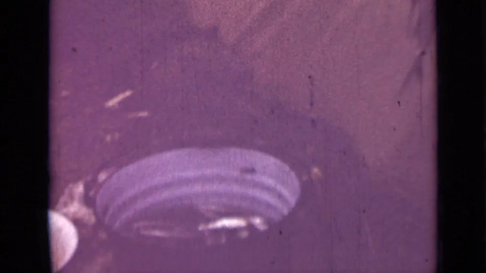 Final 1967 8mm frame where the fish has moved mostly out of view, leaving a purple surface and a striped rounded object near the bottom.