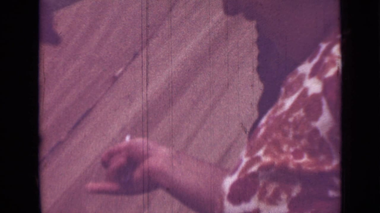 1967 Saint Petersburg home-movie frame showing hands working with a fish on a table during outdoor catch preparation.