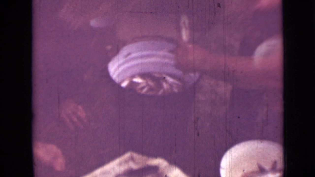 1967 Saint Petersburg frame showing hands, a white bowl, and small fish in a close domestic food-preparation moment on 8mm film.