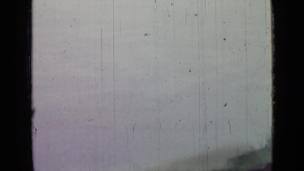 Sparse 8mm landscape frame with pale open surface and a dark shoreline form, from footage associated with Saint Petersburg in 1967.
