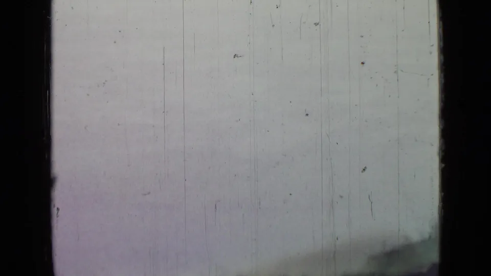 Sparse 8mm landscape frame with pale open surface and a dark shoreline form, from footage associated with Saint Petersburg in 1967.