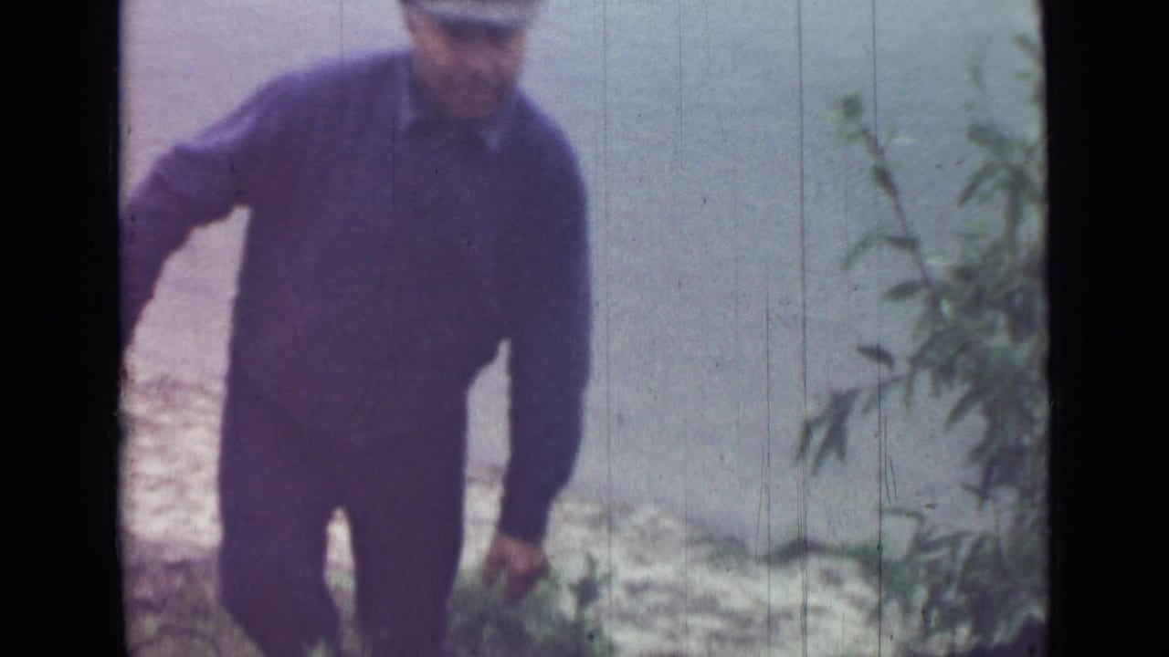 A man in dark jacket and trousers stands or steps along a small outdoor incline in the Saint Petersburg 1967 home-movie clip.