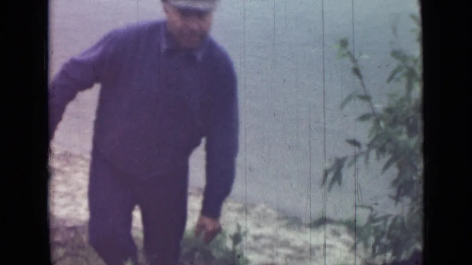 A man in dark jacket and trousers stands or steps along a small outdoor incline in the Saint Petersburg 1967 home-movie clip.