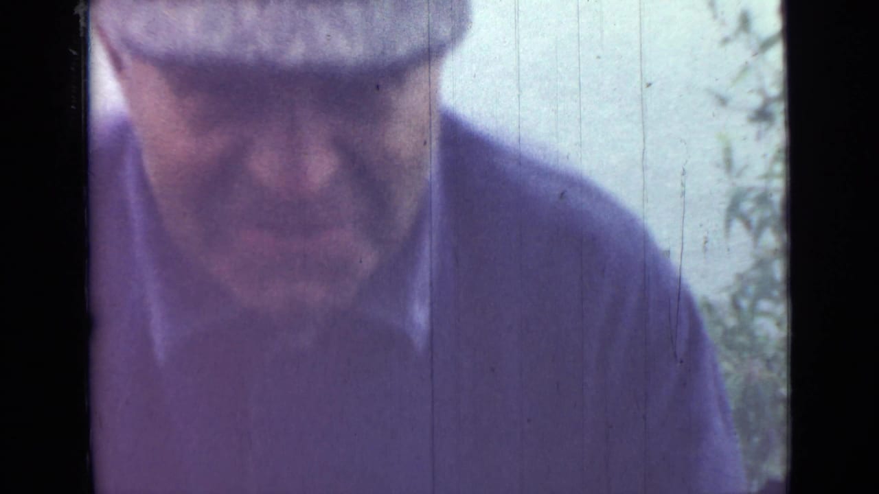 Close view of an adult man's face and cap, softly focused against a pale outdoor background.