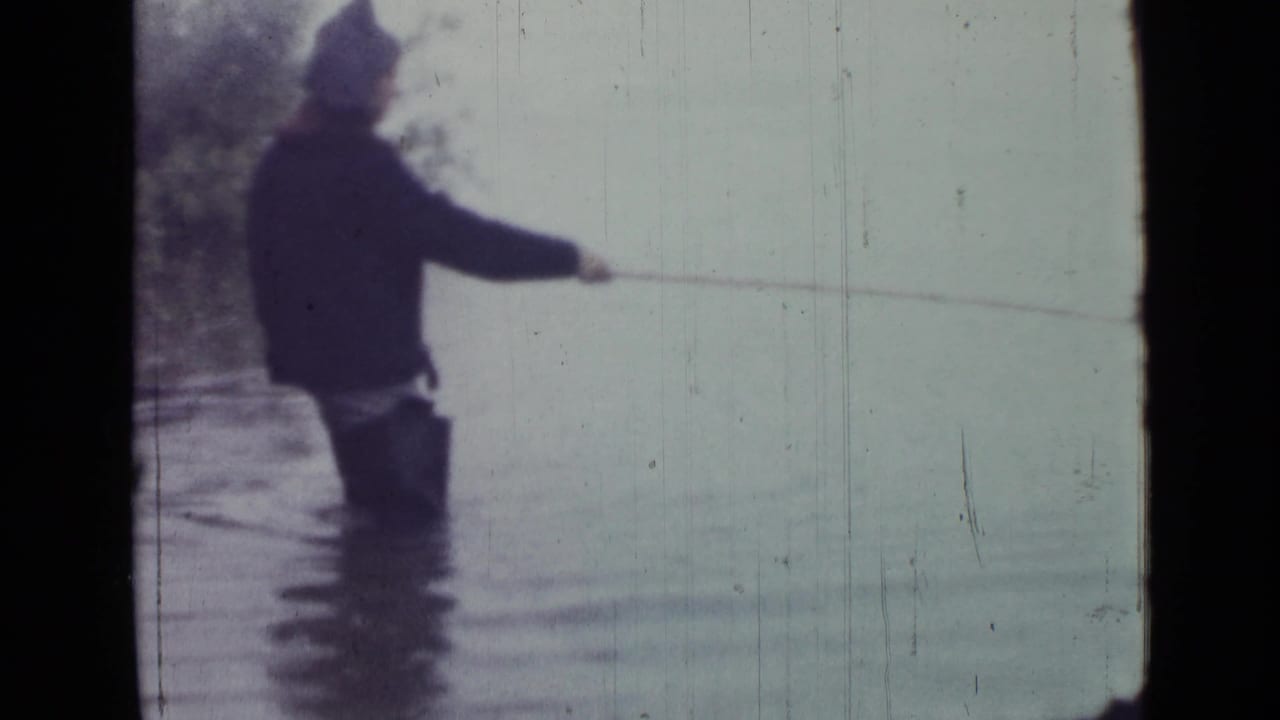 The 1967 home movie shows the man in shallow water, side-on to the camera, with a fishing line stretched across the pale lake.