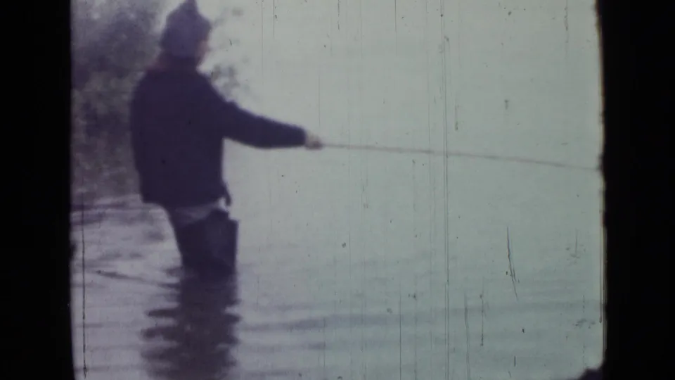 The 1967 home movie shows the man in shallow water, side-on to the camera, with a fishing line stretched across the pale lake.