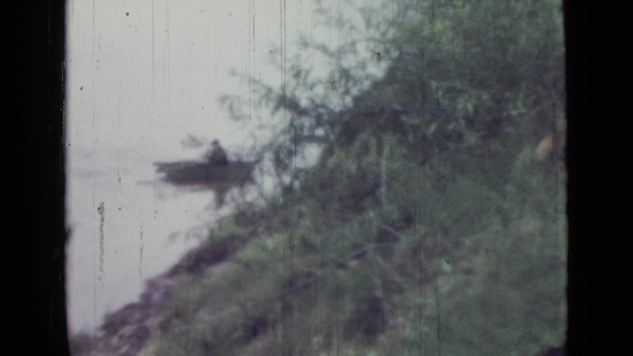1967 Saint Petersburg 8mm frame showing the rower lower in frame near a leafy shoreline and reflected water.