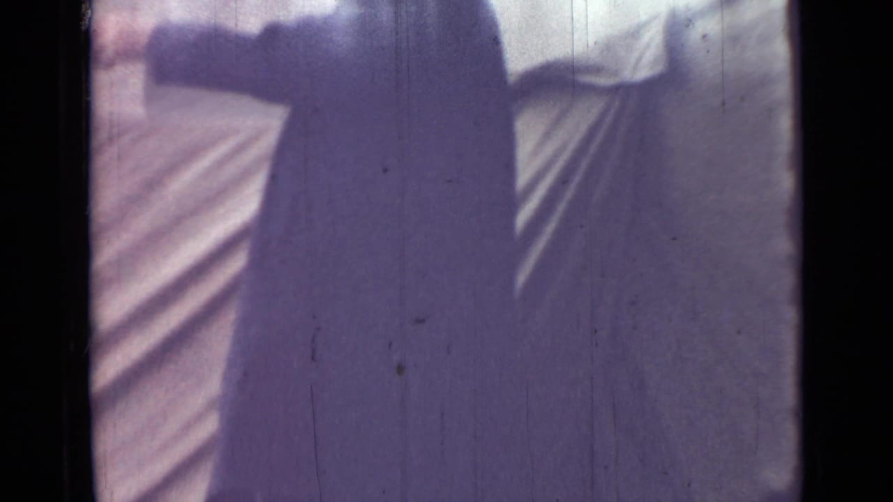 In supported 1967 Saint Petersburg footage, an adult man in a long dark coat is partly cropped near pale canvas tenting.