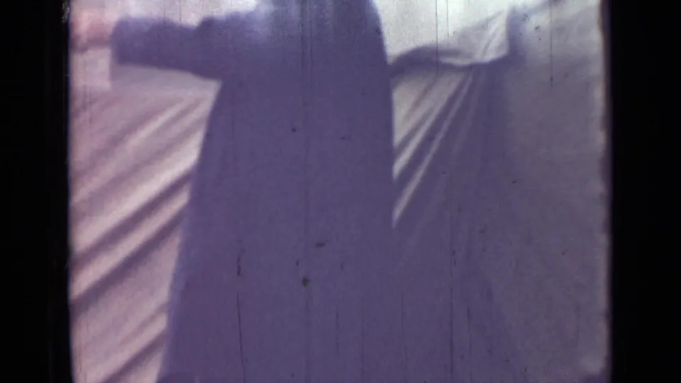 In supported 1967 Saint Petersburg footage, an adult man in a long dark coat is partly cropped near pale canvas tenting.