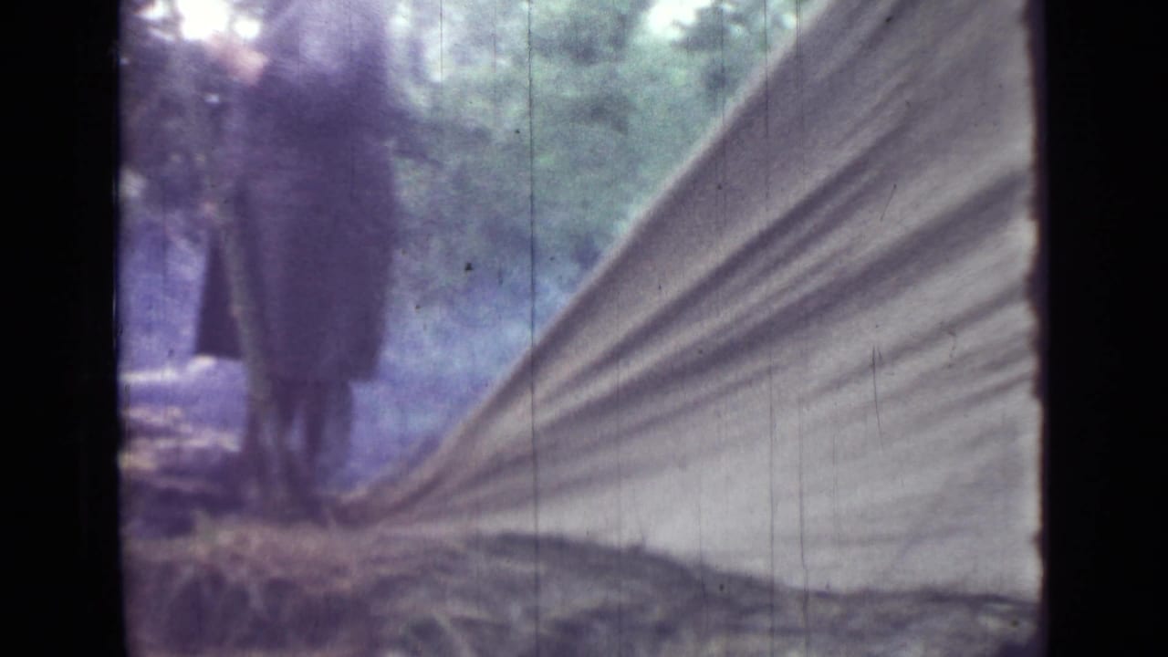 1967 home-movie frame near Saint Petersburg showing adults beside a pitched canvas tent as smoke drifts through the campsite.