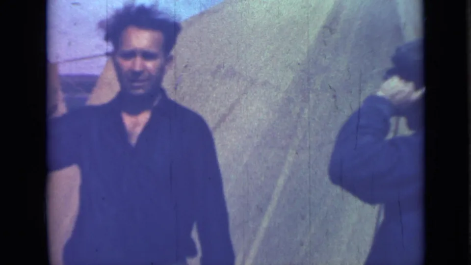 1967 Saint Petersburg 8mm frame showing the dark-shirted man closer to camera, with the capped companion partly cut off at the right edge.