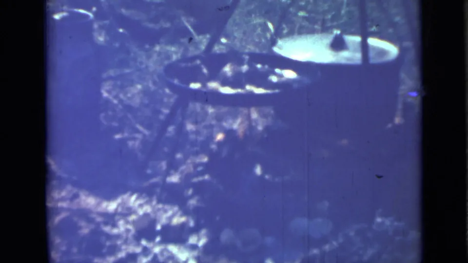 1967 Saint Petersburg 8mm frame showing tripod-mounted cookware in a quiet outdoor campfire cooking scene.